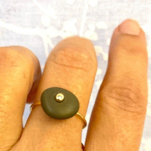 Santorini&#39;s gray pebble ring engraved with one diamond or gemstone in 18k yellow gold. Hand made ring with natural beach stone from Greece.