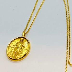Amulette ovale double face en or jaune 14 carats, Vierge Marie en relief sur le devant sur une longue chaîne. Une madone en or inspirante pour vos proches.