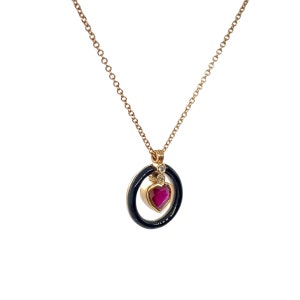 May include: A gold necklace with a black enamel circle pendant featuring a ruby heart and two small diamonds.