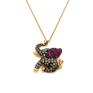 May include: A gold chain necklace with a diamond-encrusted elephant pendant. The elephant's ear is accented with pink gemstones.