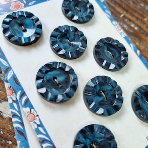 May include: A card of eight blue plastic buttons with a scalloped edge. The card has a floral pattern and the text "Cute Model" printed on it.