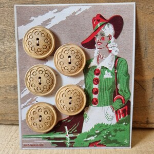 Pode incluir: Seis botões de madeira castanho-claro com um desenho floral estão dispostos numa ilustração vintage de uma mulher com um chapéu vermelho e um casaco verde. A ilustração tem um fundo castanho e branco.