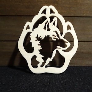 May include: A white wooden cutout of a wolf's head inside a paw print.
