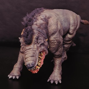 May include: A detailed, hand-painted, gray and black monster figurine with sharp teeth and claws. The monster has a textured, realistic appearance.