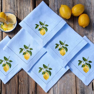 May include: Set of six blue linen napkins with embroidered lemon designs. Each napkin features a lemon branch with leaves and white blossoms.