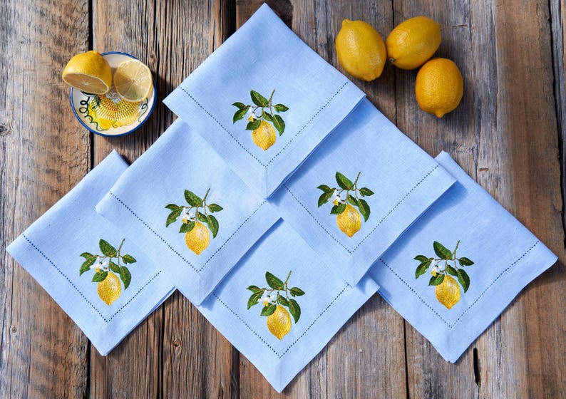 May include: Set of six blue linen napkins with embroidered lemon designs. Each napkin features a lemon branch with leaves and white blossoms.