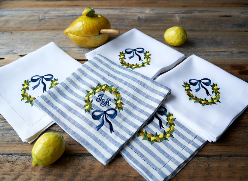 May include: Four embroidered kitchen towels with a lemon wreath design. Two towels are white with a blue bow and a lemon wreath. Two towels are blue and white striped with a blue bow and a lemon wreath. One towel has the initials "J & K" in the center of the wreath.