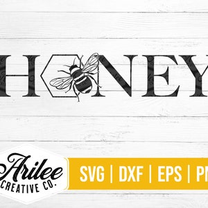 Peut inclure: Conception graphique en noir et blanc du mot "Honey" avec une abeille stylis&eacute;e &agrave; l'int&eacute;rieur d'un hexagone. Le design est sur un fond de bois blanc.