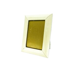 May include: A white picture frame with a textured surface. The frame has a gold-coloured mat and is designed to hold a 4x6 inch photo.