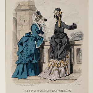 Puede incluir: Una impresi&oacute;n antigua titulada "LE JOURNAL DES DAMES ET DES DEMOISELLES" representa a dos mujeres con vestidos de &eacute;poca. Una mujer con un vestido verde azulado usa un telescopio, mientras que la otra con un vestido negro se&ntilde;ala el horizonte. La impresi&oacute;n tiene una est&eacute;tica vintage.