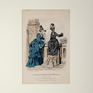 Puede incluir: Una impresi&oacute;n antigua titulada "Le Journal des Dames et des Demoiselles" con dos mujeres con vestidos elaborados en un balc&oacute;n. Una mujer lleva un vestido verde azulado, la otra un vestido negro con detalles amarillos. La impresi&oacute;n est&aacute; enmarcada.