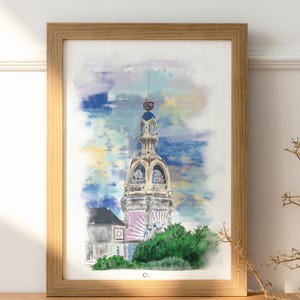 Peut inclure: Peinture à l'aquarelle d'un grand bâtiment orné avec une tour, encadrée dans du bois clair. L'œuvre présente une palette de couleurs pastel avec des teintes bleues, jaunes et roses. Le feuillage vert est à la base du bâtiment.