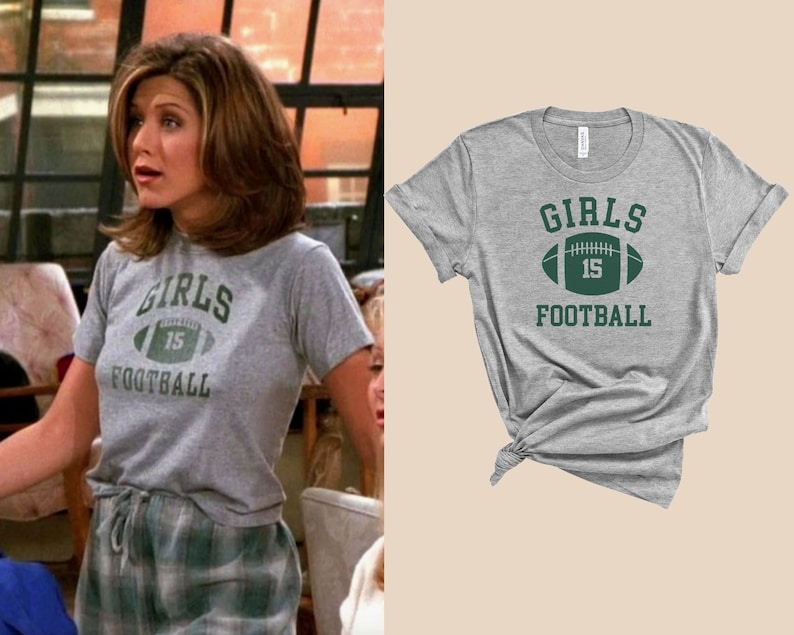 May include: A gray t-shirt with a green football graphic and the text "Girls 15 Football".