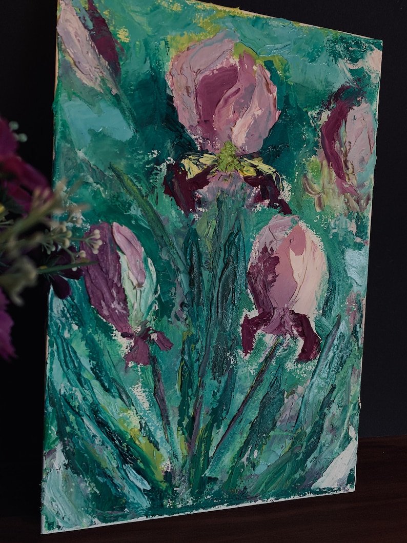May include: A painting of purple irises with green leaves on a white canvas. The flowers are painted in a thick, textured style.