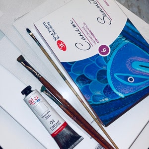May include: A set of 9 acrylic paints in a blue and white box with the brand name "Sonnet" and the text "Художественные акриловые краски" in Cyrillic script. The box is sitting on a white surface with two paintbrushes and a tube of titanium white oil paint.