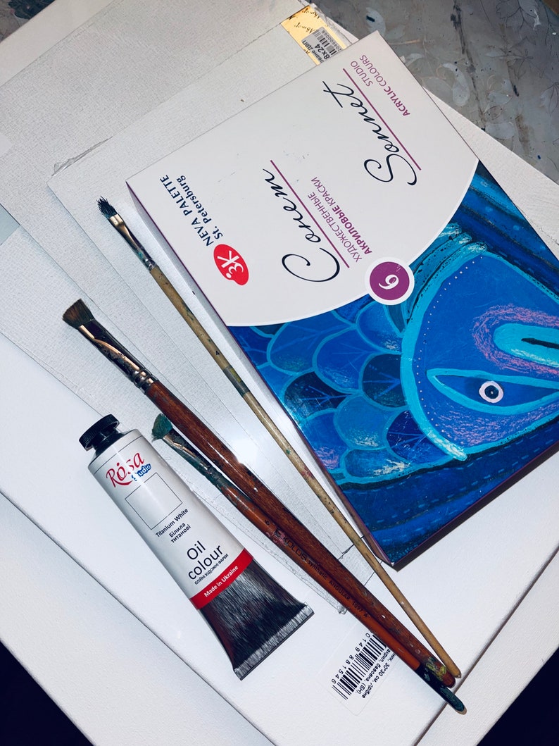 May include: A set of 9 acrylic paints in a blue and white box with the brand name "Sonnet" and the text "Художественные акриловые краски" in Cyrillic script. The box is sitting on a white surface with two paintbrushes and a tube of titanium white oil paint.