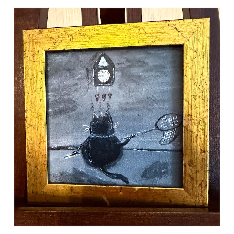 Puede incluir: Pintura enmarcada en oro que representa un gato negro con una red de mariposas, apuntando a un reloj de cuco. El fondo es gris y blanco. La obra de arte tiene un estilo ilustrativo y caprichoso, con un tema l&uacute;dico.