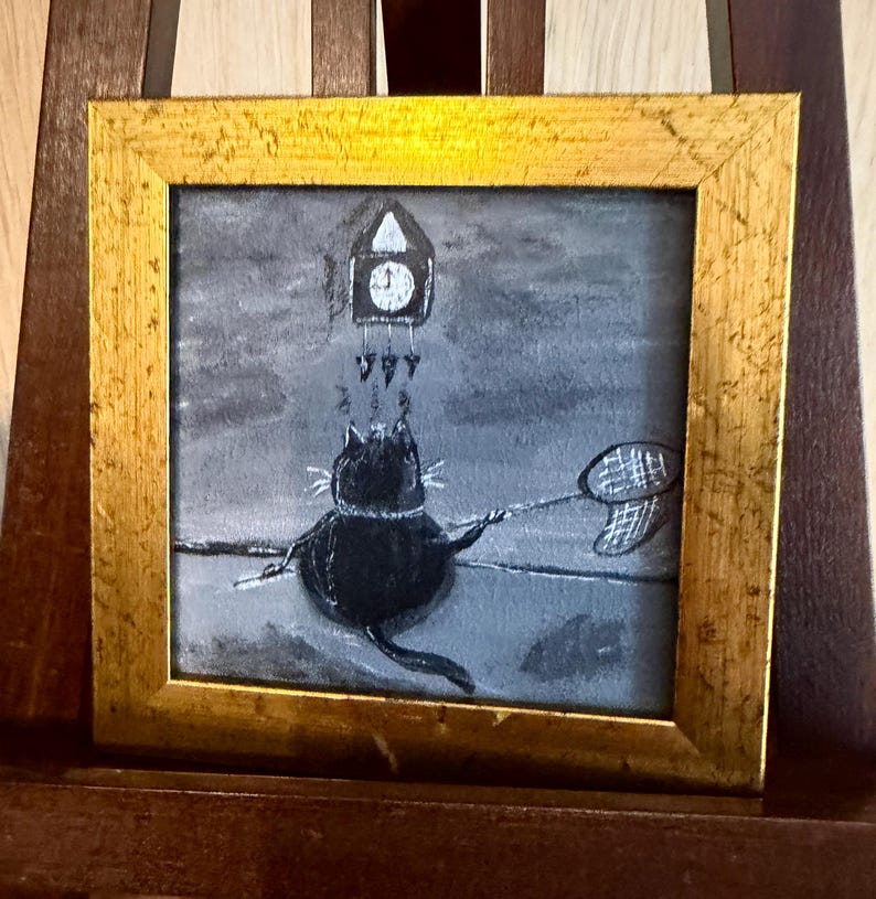 Puede incluir: Pintura enmarcada que representa un gato negro que intenta atrapar un reloj con una red de mariposas. La obra de arte est&aacute; en escala de grises con un marco dorado. El gato es el foco, con el reloj y la red.