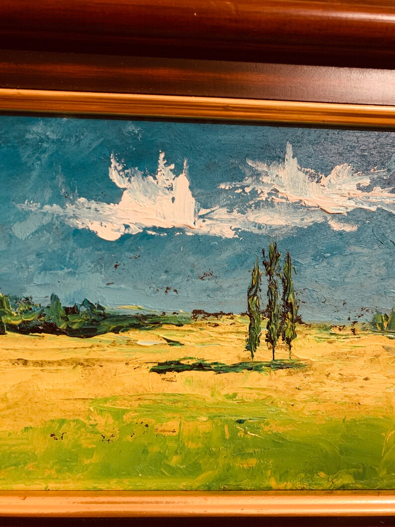 May include: A painting of a landscape with a blue sky, white clouds, and three green trees in the foreground. The field is a yellow-green color.