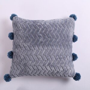 May include: Gray throw pillow with a textured chevron pattern and blue pom-poms around the edges.