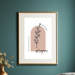 May include: A framed print with a minimalist design featuring a stylized branch with leaves in black against a blush pink background. The text "יהיו לָנוּ לְרִפְאוּת" is written in Hebrew in a black font. The text "For the healing of the nation" is written in English in a smaller black font.