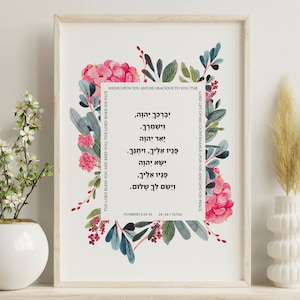 Könnte beinhalten: Ein druckbares Wandbild mit einem floralen Rahmen aus rosa und blauen Blumen. Das Design enthält einen hebräischen Text aus Numeri 6:24-26, der übersetzt "Der Herr segne dich und behüte dich; der Herr lasse sein Angesicht leuchten über dir und sei dir gnädig; der Herr hebe sein Angesicht über dich und gebe dir Frieden." bedeutet.