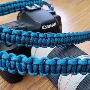 May include: A teal blue camera strap made of paracord, with a Canon camera attached.