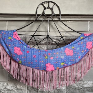 May include: A blue fabric garment with a pink fringe trim. The fabric has a pattern of pink clouds, stars, and diamonds on a blue background.