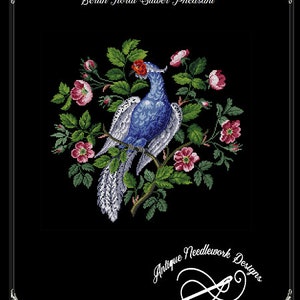 May include: A cross-stitch design featuring a blue and white pheasant perched on a branch, surrounded by pink roses and green leaves. The text "Berlin Floral Silver Pheasant" is at the top, with "Antique Needlework Designs" at the bottom.