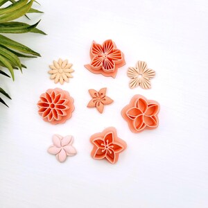 Peut inclure: Un ensemble de huit emporte-pièces en forme de fleurs dans des tons pêche, corail et rose clair. Le lot comprend différents motifs de pétales, allant de simples fleurs à cinq pétales à des designs floraux complexes à plusieurs couches.