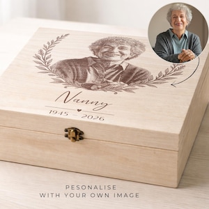 May include: A light-coloured wooden box featuring a portrait of a woman and the word "Nanny" engraved on the lid. The box has a metal clasp and the years 1945-2026 are also engraved. The text "PERSONALIZE WITH YOUR OWN IMAGE" is at the bottom.
