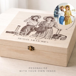 May include: A light-colored wooden keepsake box featuring a laser-engraved illustration of two people with hats and luggage. The text "Rose & Jade's TRAVEL MEMORIES" is engraved below the image. A small circular inset shows the original color photograph.