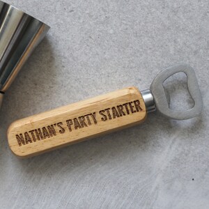 May include: A wooden bottle opener with a metal bottle opener attached to the end. The wooden handle is engraved with the text "Nathan's Party Starter".