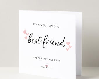 Op de afbeelding: Een witte kaart met roze hartjes en zwarte tekst die "To a very special best friend Happy Birthday Katy" zegt.
