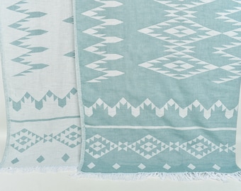 May include: A light blue and white patterned throw blanket with fringe on the bottom edge.