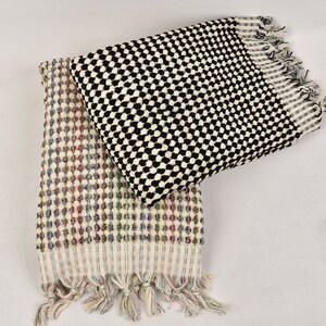 May include: Two Turkish towels with fringe edges. One towel is black and white with a checkered pattern. The other towel is white with a multi-colored checkered pattern.