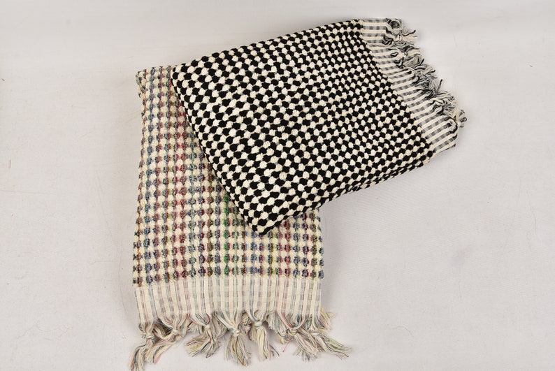 May include: Two Turkish towels with fringe edges. One towel is black and white with a checkered pattern. The other towel is white with a multi-colored checkered pattern.