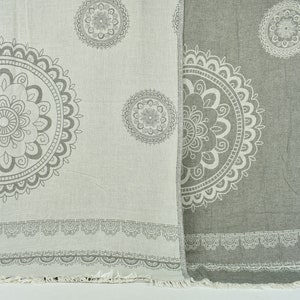 May include: Two woven cotton throws with a gray and white mandala pattern. The throw on the left is white with gray mandalas, and the throw on the right is gray with white mandalas.