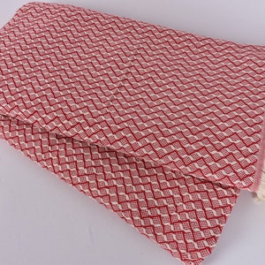 May include: Red and white patterned throw blanket with fringe. The blanket is folded in half and has a diamond pattern.