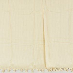 May include: A cream-colored throw blanket with a woven texture and fringe trim.