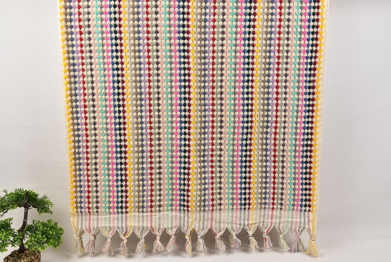 May include: A colorful striped hand towel with a fringe border. The towel is made of a soft, absorbent material and features a variety of colors, including pink, blue, green, yellow, and red.