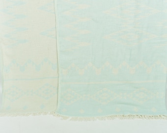 May include: Two woven cotton throws with a subtle pattern. One throw is white with a light blue pattern, and the other is light blue with a white pattern.