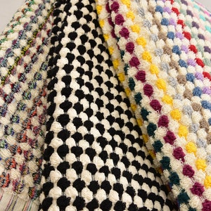 May include: Four different bath mats with various patterns. The first mat has a black and white checkered pattern. The second mat has a colorful pattern with red, blue, yellow, and green. The third mat has a white background with a colorful pattern of red, yellow, blue, and purple. The fourth mat has a white background with a colorful pattern of red, yellow, blue, and green.