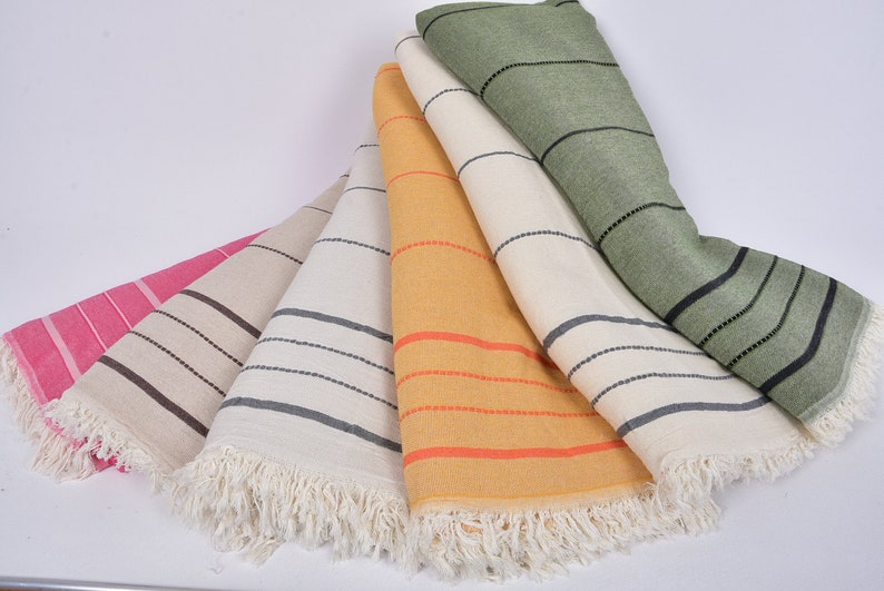 May include: Five striped towels in different colors, including pink, beige, yellow, and green, with black stripes and white fringe.
