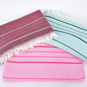 May include: Three striped towels in different colors: pink with hot pink stripes, light blue with black stripes, and burgundy with gray stripes. The towels have white fringe.