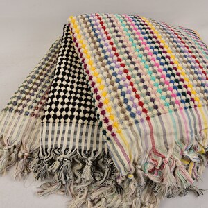 May include: A stack of four Turkish towels with colorful striped and patterned designs. The towels have fringe edges and are made of cotton.