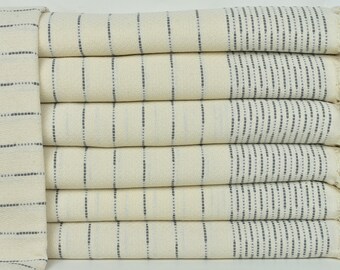 May include: A stack of six cream-colored towels with thin black stripes. The towels have a fringe on the ends.