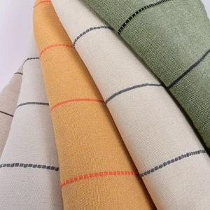 May include: Five fabric swatches with black and white stripes. The swatches are folded and stacked on top of each other. The top swatch is green, the next is beige, the next is yellow, the next is beige, and the bottom swatch is pink.