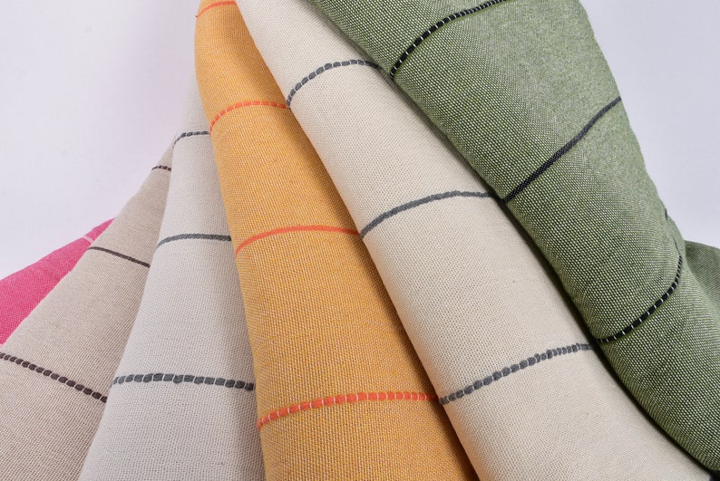 May include: Five fabric swatches with black and white stripes. The swatches are folded and stacked on top of each other. The top swatch is green, the next is beige, the next is yellow, the next is beige, and the bottom swatch is pink.