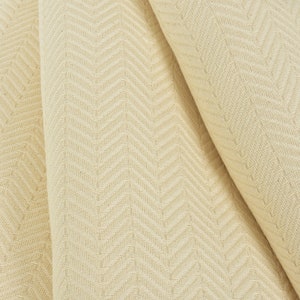 May include: Cream-colored fabric with a subtle herringbone pattern. The fabric is folded in thirds, showing the texture and weave.